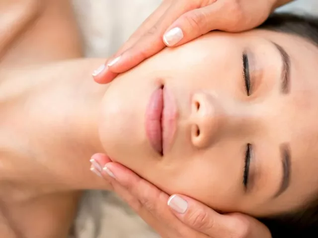 Overhead shot of woman with beautiful skin after microinfusion macial with esthetician holding her face