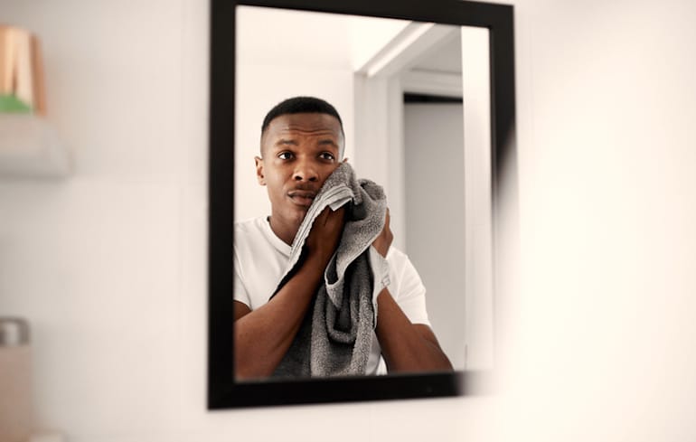 man looking for signs of dehydrated skin after washing face