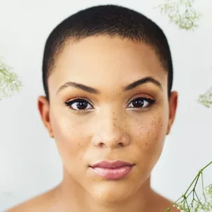 Woman with cropped hair and nose ring amongst delicate flowers