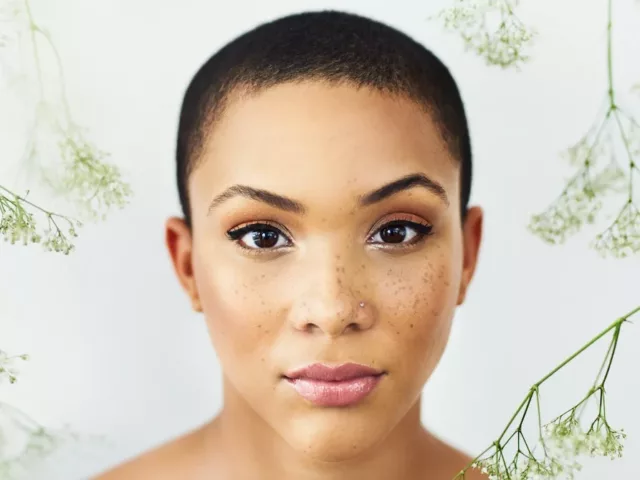 Woman with cropped hair and nose ring amongst delicate flowers