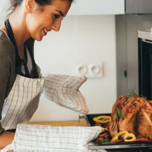 Young woman taking dinner out of the oven