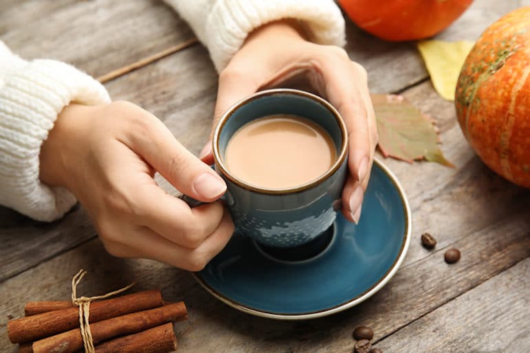 Woman holding mug of a homemade healthy pumpkin spice latte