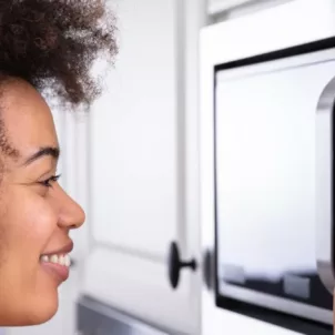 Smiling woman microwaving her food