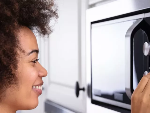 Smiling woman microwaving her food