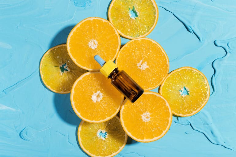 Orange Slices and Vitamin C Serum on Bright Blue Background