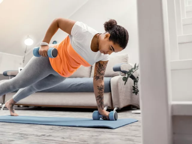 Woman doing a full body workout at home with dumbbells