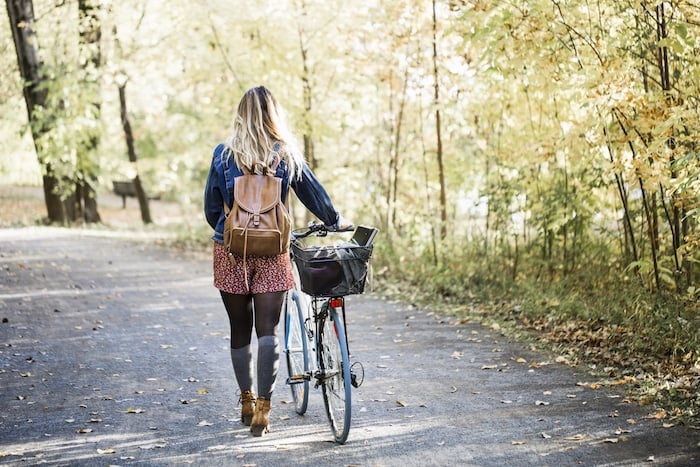 Healthy lifestyle woman walking with bike in fall