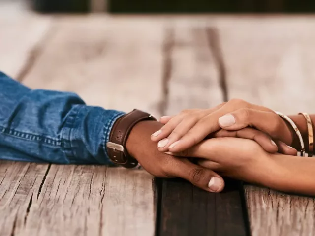 Couple holding hands on wooden table