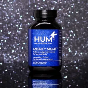 Bottle of HUM Nutrition Mighty Night supplement for skin cell renewal amidst dark starry background