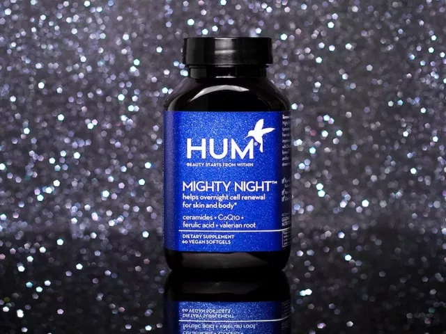 Bottle of HUM Nutrition Mighty Night supplement for skin cell renewal amidst dark starry background