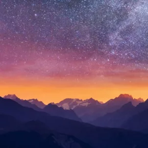 Purple pink and orange starry night sky in the mountains