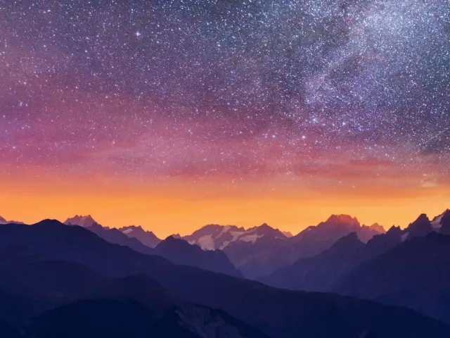 Purple pink and orange starry night sky in the mountains