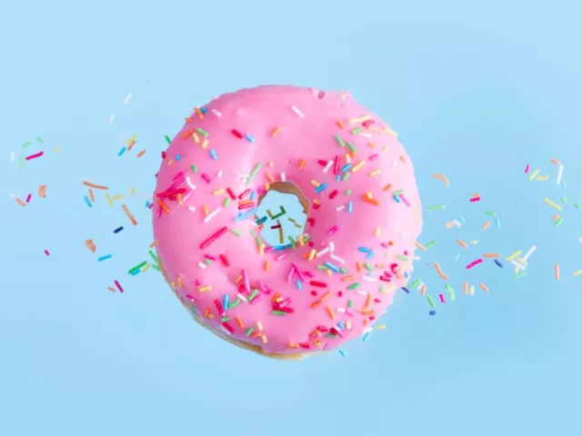 Pink donut floating over blue background