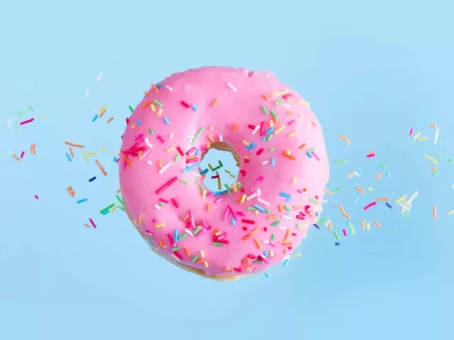 Pink donut floating over blue background