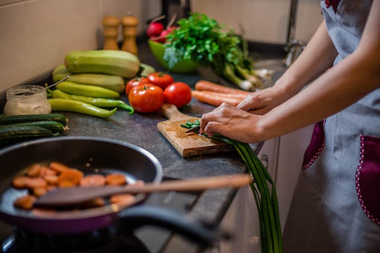 Woman chopping vegetables to cook on skillet