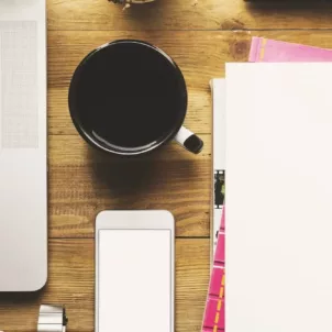 Desk with laptop, coffee, phone, and notebooks organized for optimal productivity