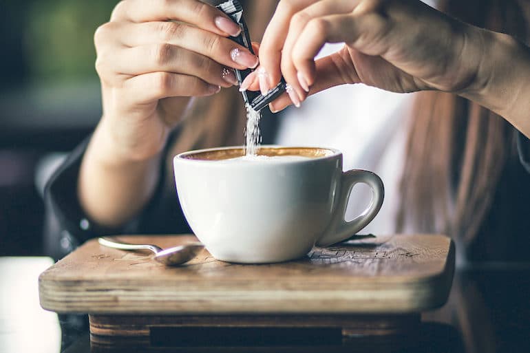 Woman adding sugar to her coffee