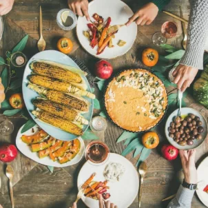 large table of people getting food at a vegan Thanksgiving dinner