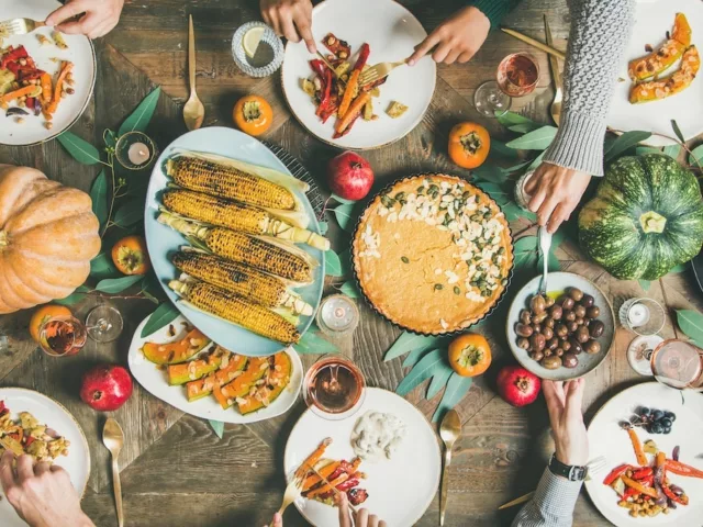 large table of people getting food at a vegan Thanksgiving dinner