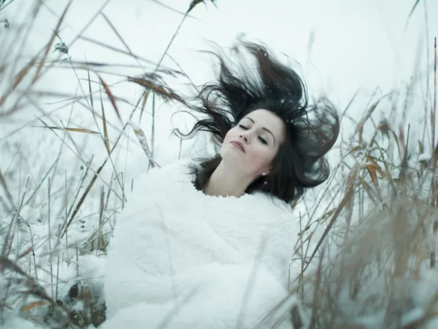 Woman flipping her dark hair in a field in winter