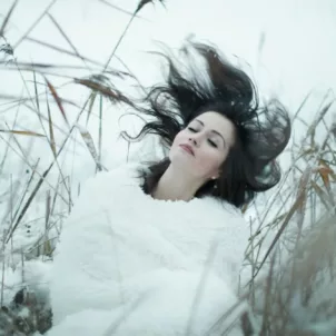 Woman flipping her dark hair in a field in winter