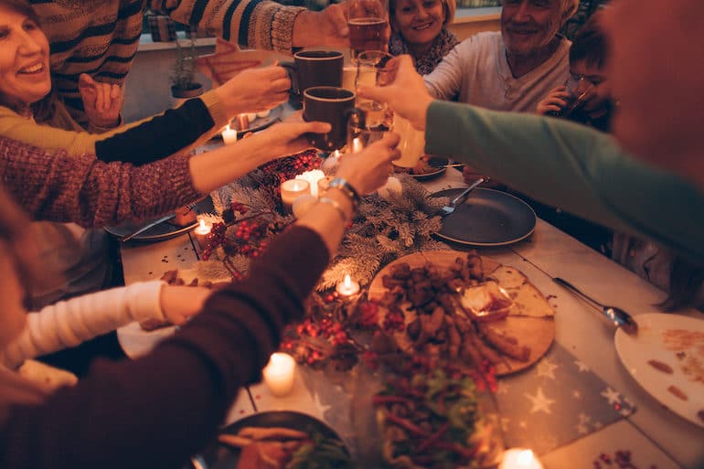 Family at Thanksgiving dinner table giving cheers and avoiding holiday conflicts