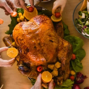 High angle shot of family members decorating Thanksgiving turkey with citrus