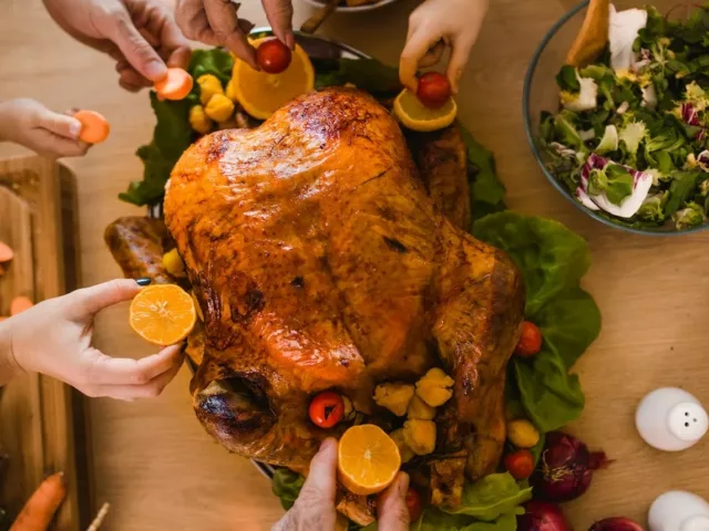 High angle shot of family members decorating Thanksgiving turkey with citrus