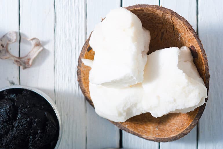 Chunks of shea butter in wooden bowl on white wood table