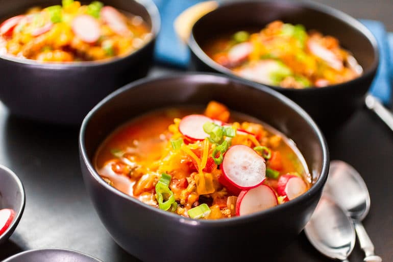 Turkey chili garnished with fresh radishes, green onions and cheddar cheese