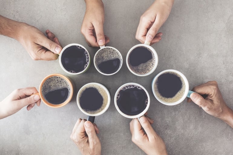 Overhead group shot of people's hands holding coffee mugs