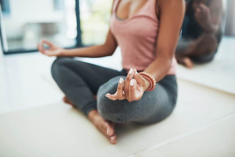 Woman meditating with hand mudras in group meditation setting