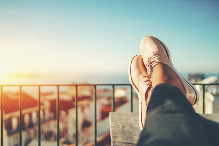 Woman with feet up on balcony enjoying the present moment on a social media detox