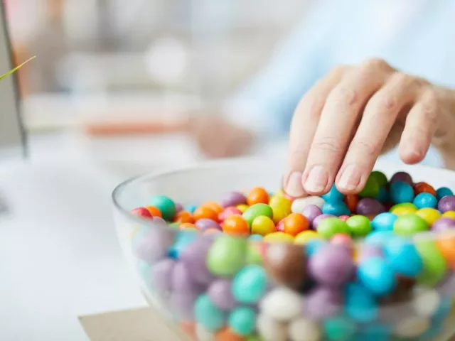 Woman's hand reaching for candy while working