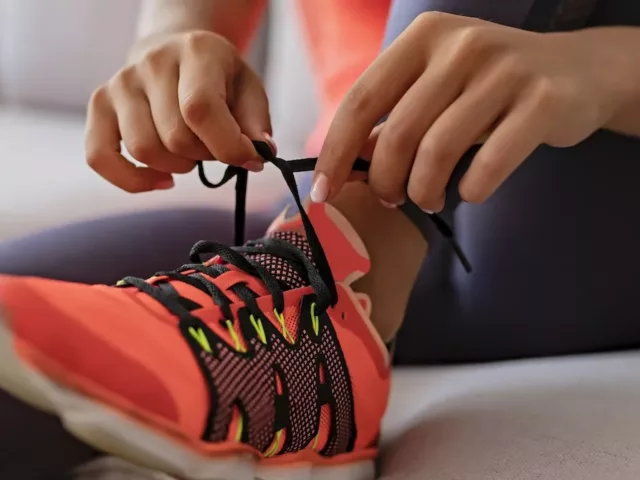 Woman tying running shoes for 2020 resolution to run more.