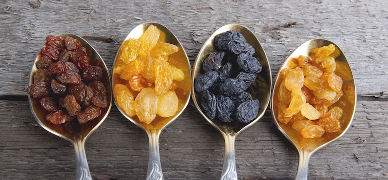 Four spoonfuls of dried fruit on wooden table