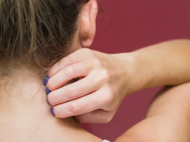 Back of woman scratching her neck