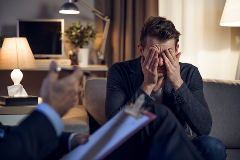 Man covering his face in psychodermatology therapy session