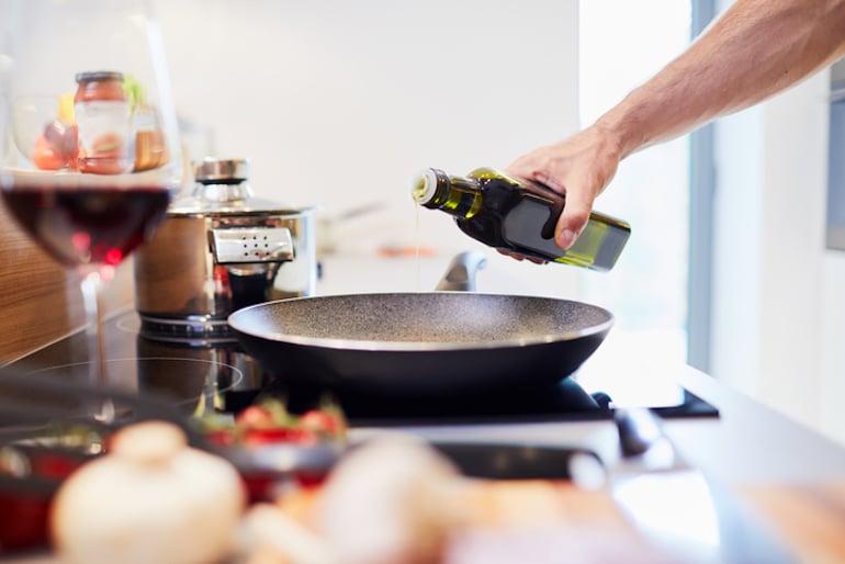 Man pouring unhealthy oil into pan on stove