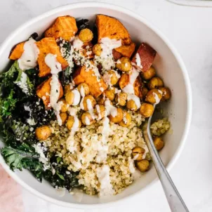 Vegan quinoa bowl with sweet potatoes, chickpeas, kale, and tahini