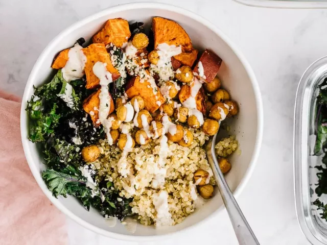 Vegan quinoa bowl with sweet potatoes, chickpeas, kale, and tahini