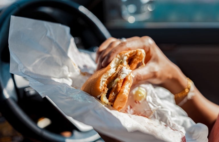 Man eating fast food in the car, which may contribute to acne