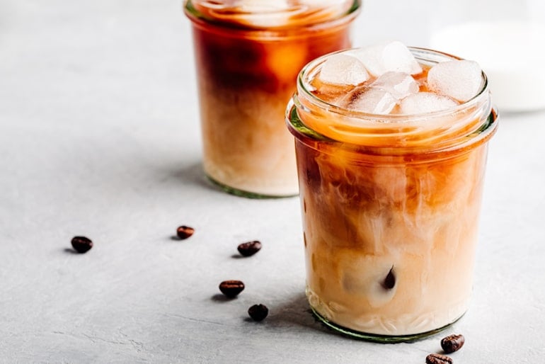 Two cold brew coffee lattes with beans