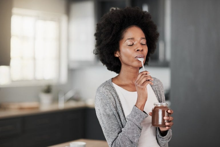 Woman indulging in her chocolate food craving in the kitchen