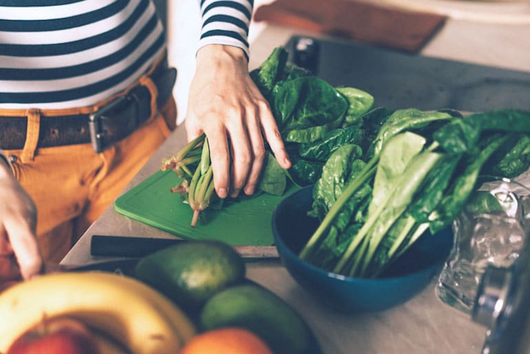 Woman preparing spinach, a leafy green that helps promote hormone balance