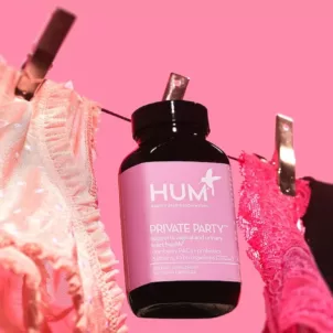 HUM Nutrition Private Party probiotic for vaginal health on clothing line with lingerie over pink background