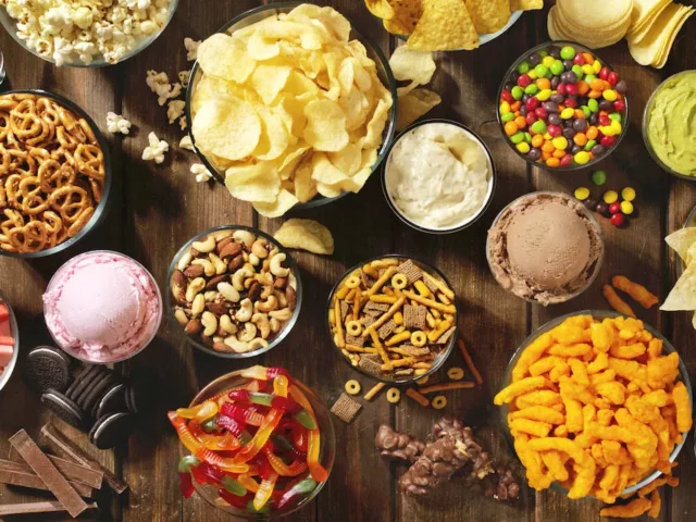 Table full of food craving unhealthy foods like chips, candy, and pretzels