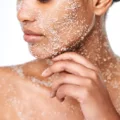 Woman using physical exfoliants on her face, neck, and decolletage