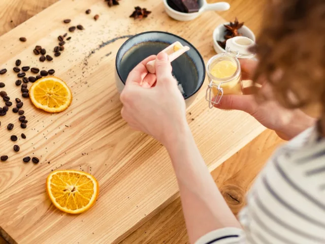 Woman making DIY beauty recipes with sugar, lemon, coffee, and other pantry staples