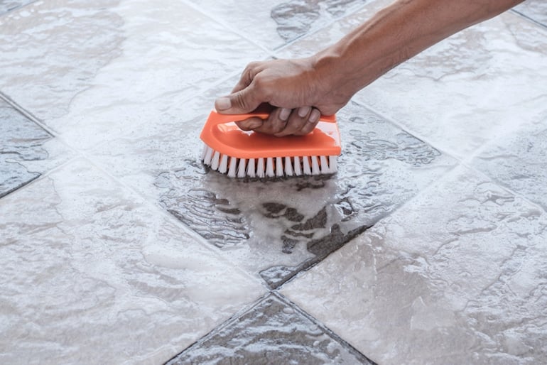 Man scrubbing the floor with a brush, keeping busy while social distancing